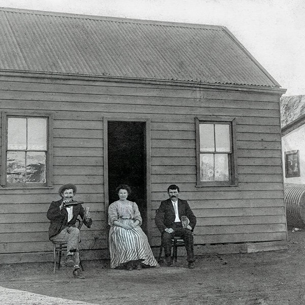 Ivan and Maria Tomich’s home in Boulder, 1912. They are celebrating the recent completion of their home on the Boulder Leases. Slime dumps can be seen in the background. Photo courtesy Alma Smith (after processing).