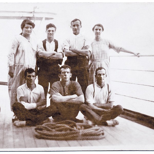A picture showing Milenko (Mick) Garbin among a group of male and female passengers (four standing and three sitting cross-legged with arms folded) looking toward the camera on the outer deck of a ship en route to Western Australia, circa 1906. Photograph courtesy Peter Garbin and Jennifer Reid.