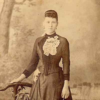 A vintage picture of a young woman in a corseted dress.